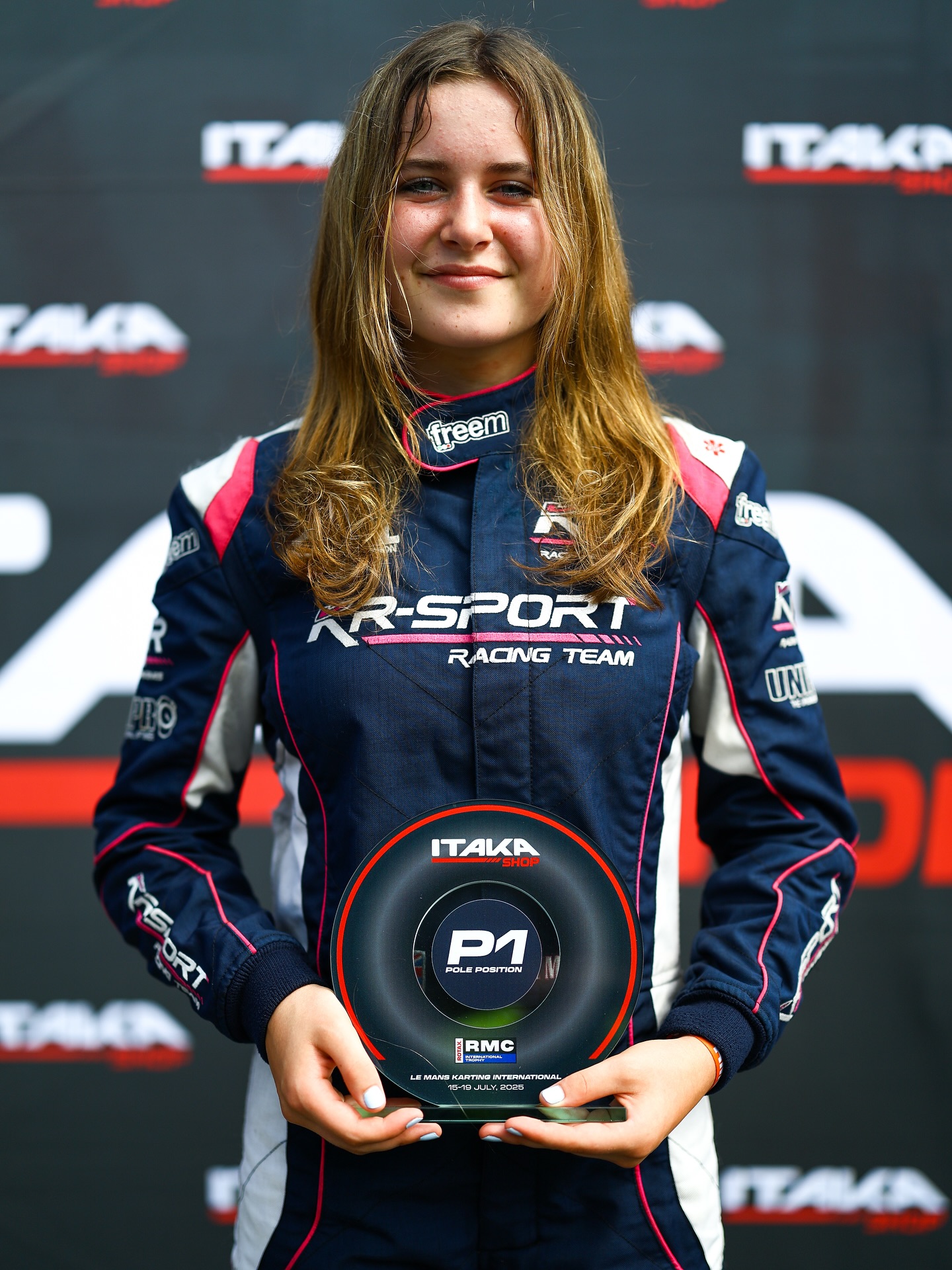Eva in her KR-Sport race suit holding the P1 pole position trophy from the RMC International Trophy at Le Mans